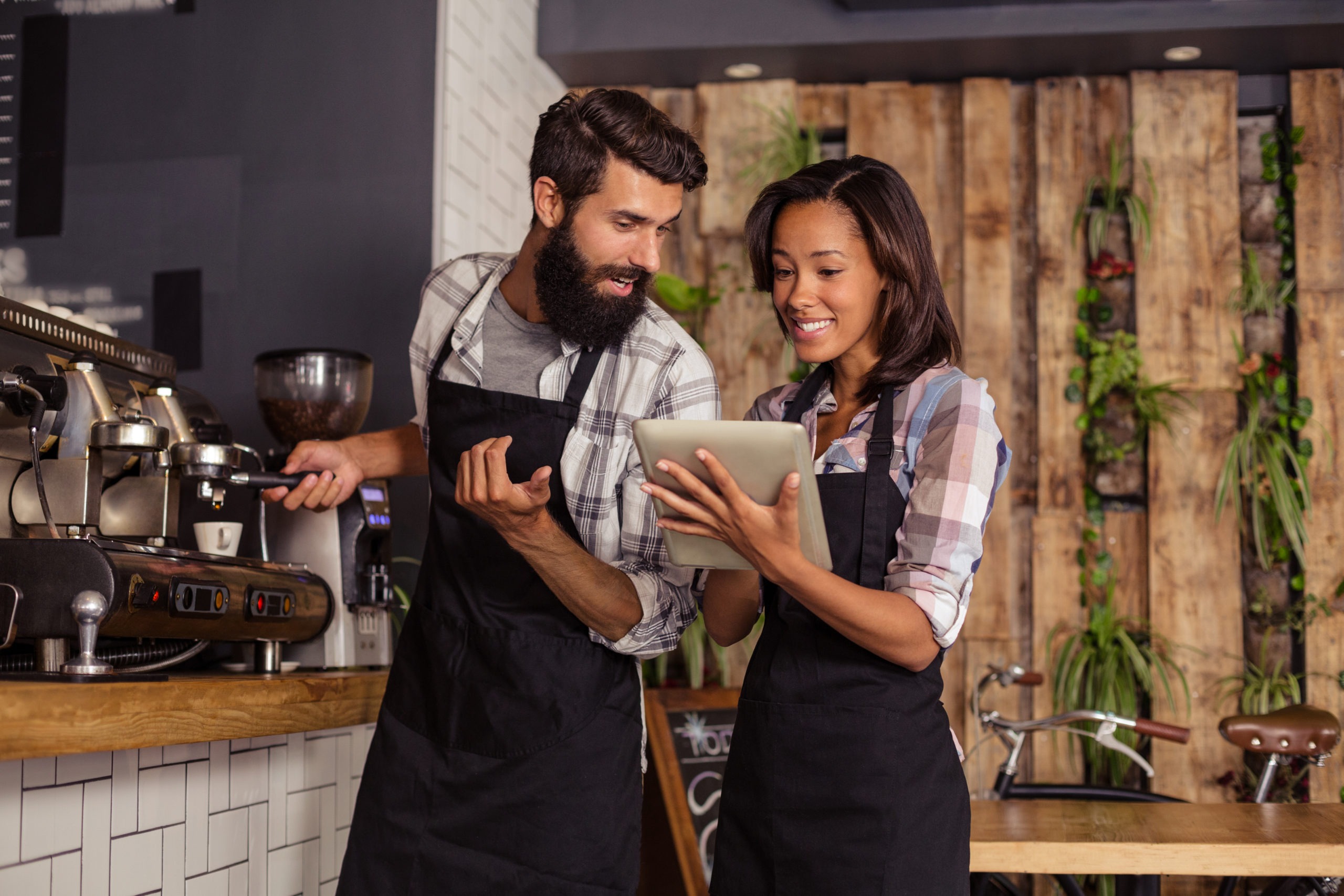 Waiter and waitresses using laptop while working in cafÃ©